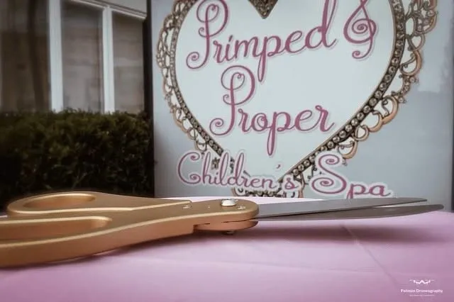The Primped and Proper heart sign with gold scissors on a pink table